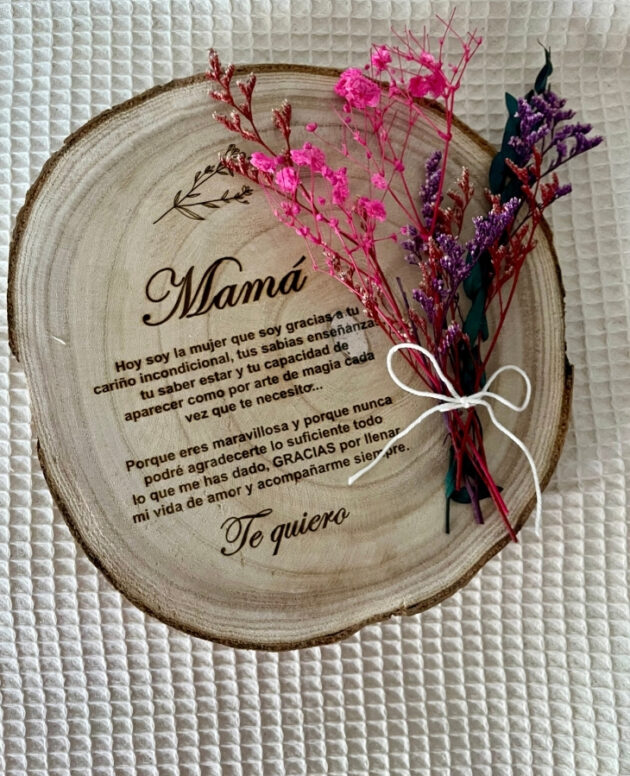 Rodaja de madera grabada con dedicatoria y flores preservadas